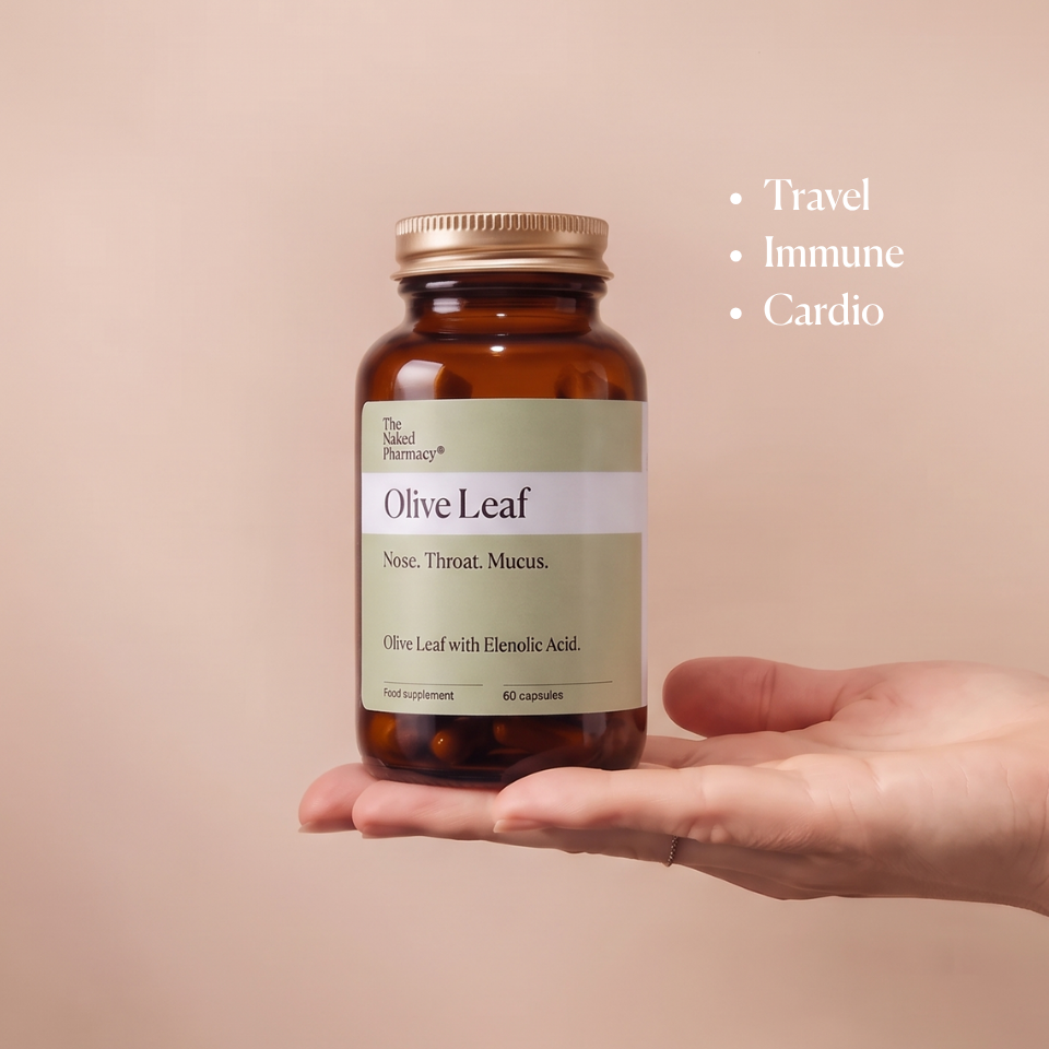 A hand holding an amber supplement bottle labeled 'Olive Leaf' by The Naked Pharmacy, set against a warm beige background with bullet points reading 'Travel', 'Immune', and 'Cardio'.