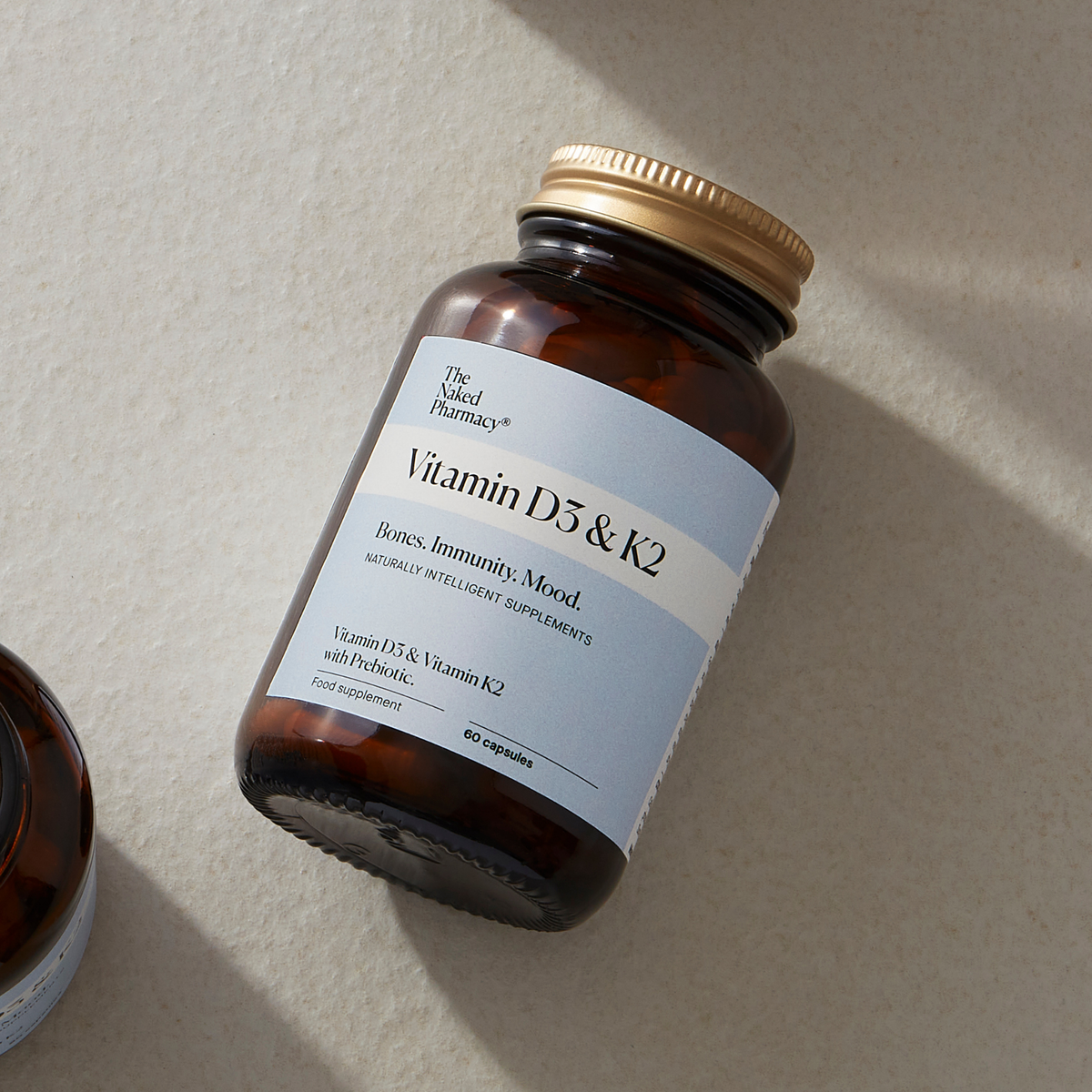 An amber glass supplement bottle labeled 'The Naked Pharmacy Vitamin D3 & K2' 
