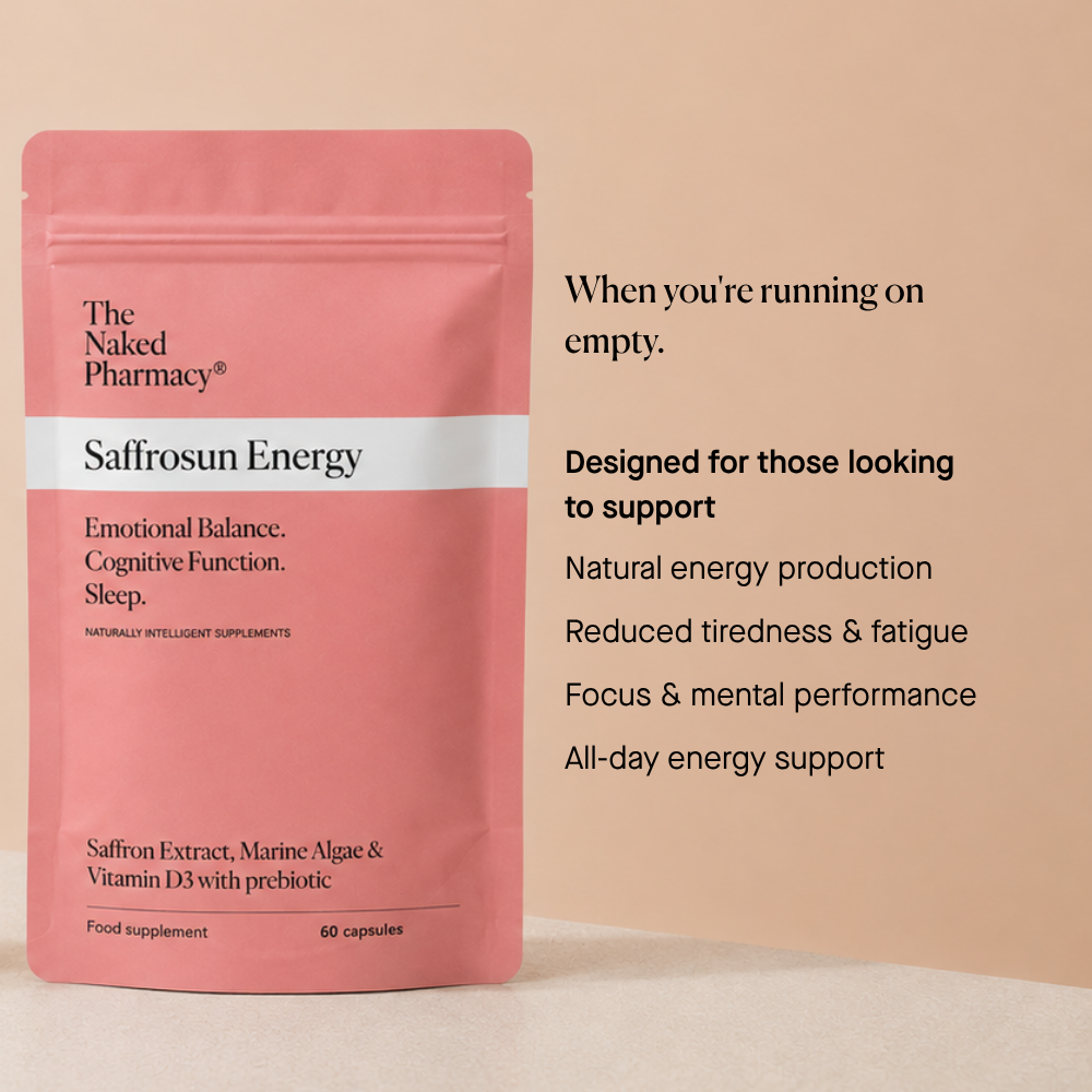 A pink stand-up supplement pouch labeled 'The Naked Pharmacy Saffrosun Energy' stands on a beige surface against a peach background, with marketing text to the right describing cognitive support and energy benefits.